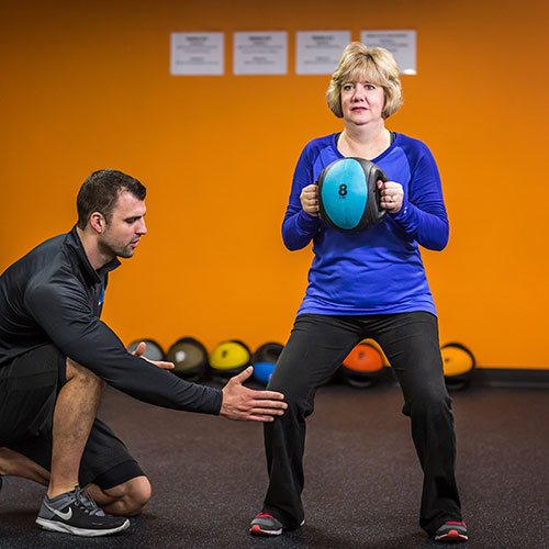 woman being coached on squatting by afs coach