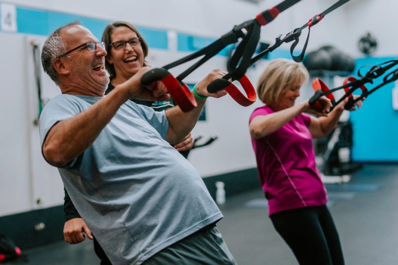 A man enjoying his workout and smiling while performing resistance band rows