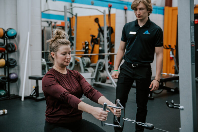 Member performing strength exercises while coach watches